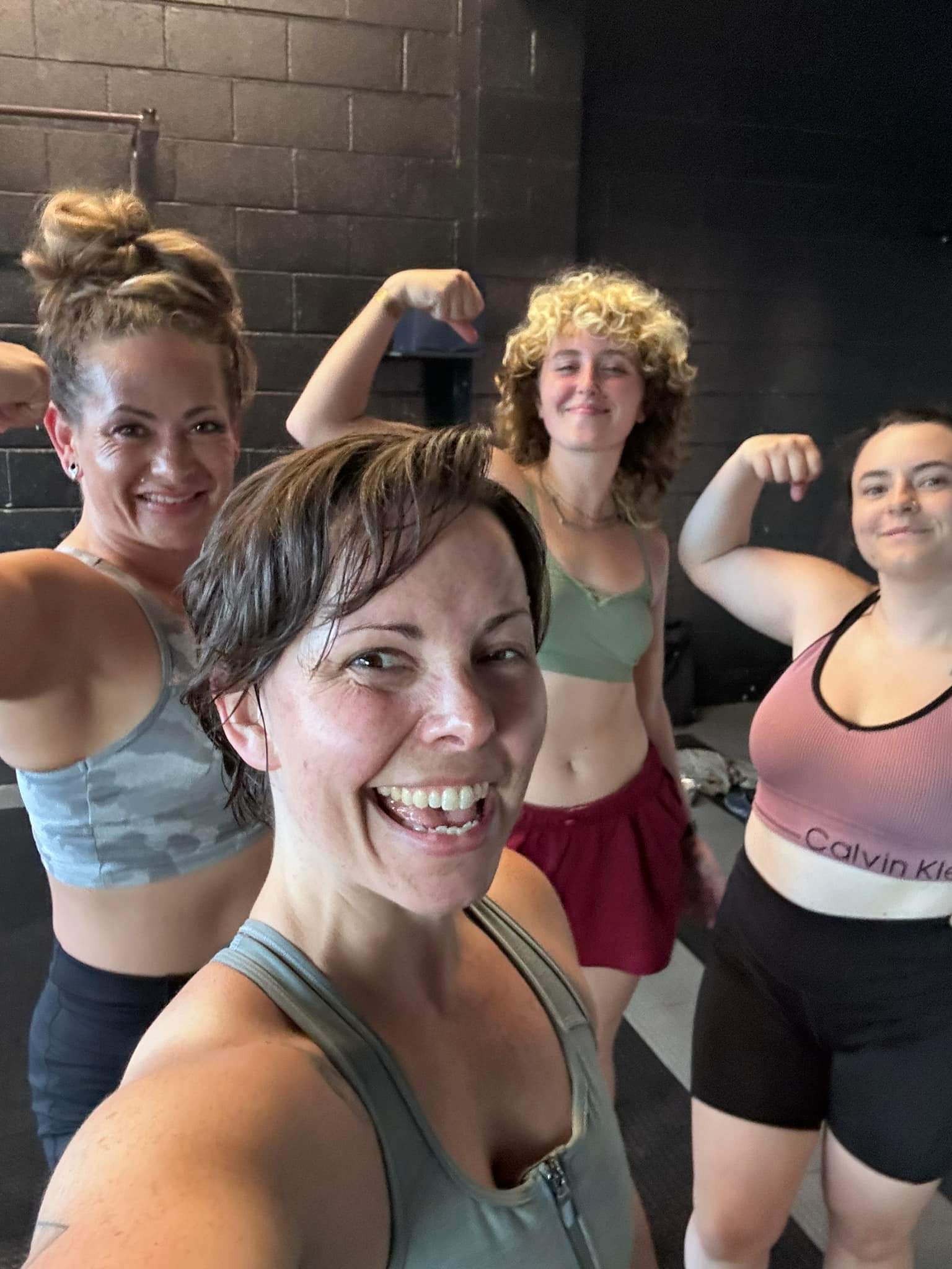 katie murray and 3 women flexing muscles after a workout